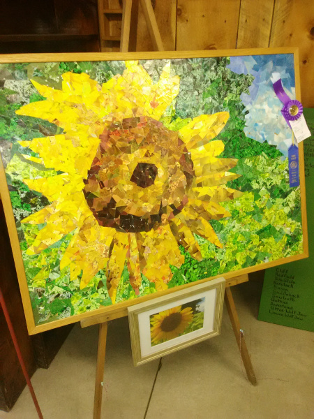 A large sunflower artwork on an easel.