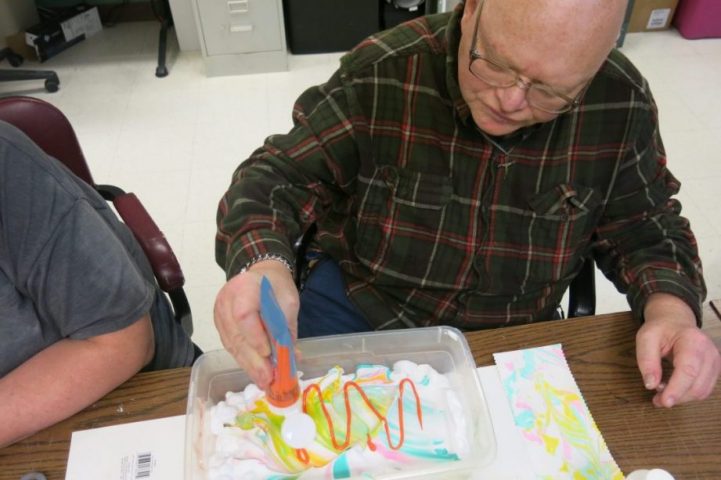 Older man creating a painting.